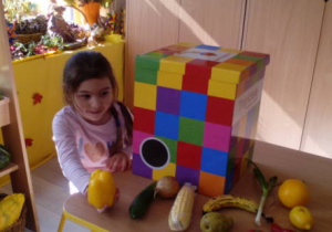 Dziewczynka pokazuje odgadnięte warzywo- żółtą paprykę.